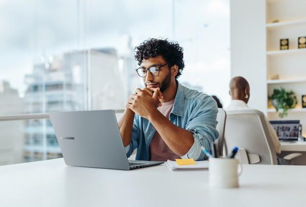 A man sitting at a desk looking at his laptop.